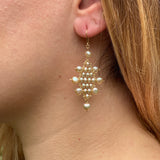 Model wearing large Kilim earrings in champagne pearls and gold