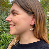 Model wearing small Kilim earrings in gold and champagne pearls